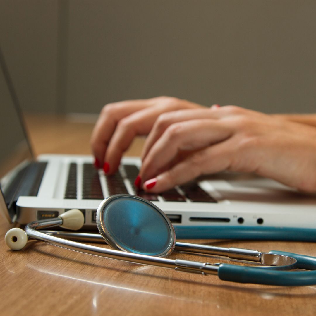 on a laptop with a stethoscope on desk
